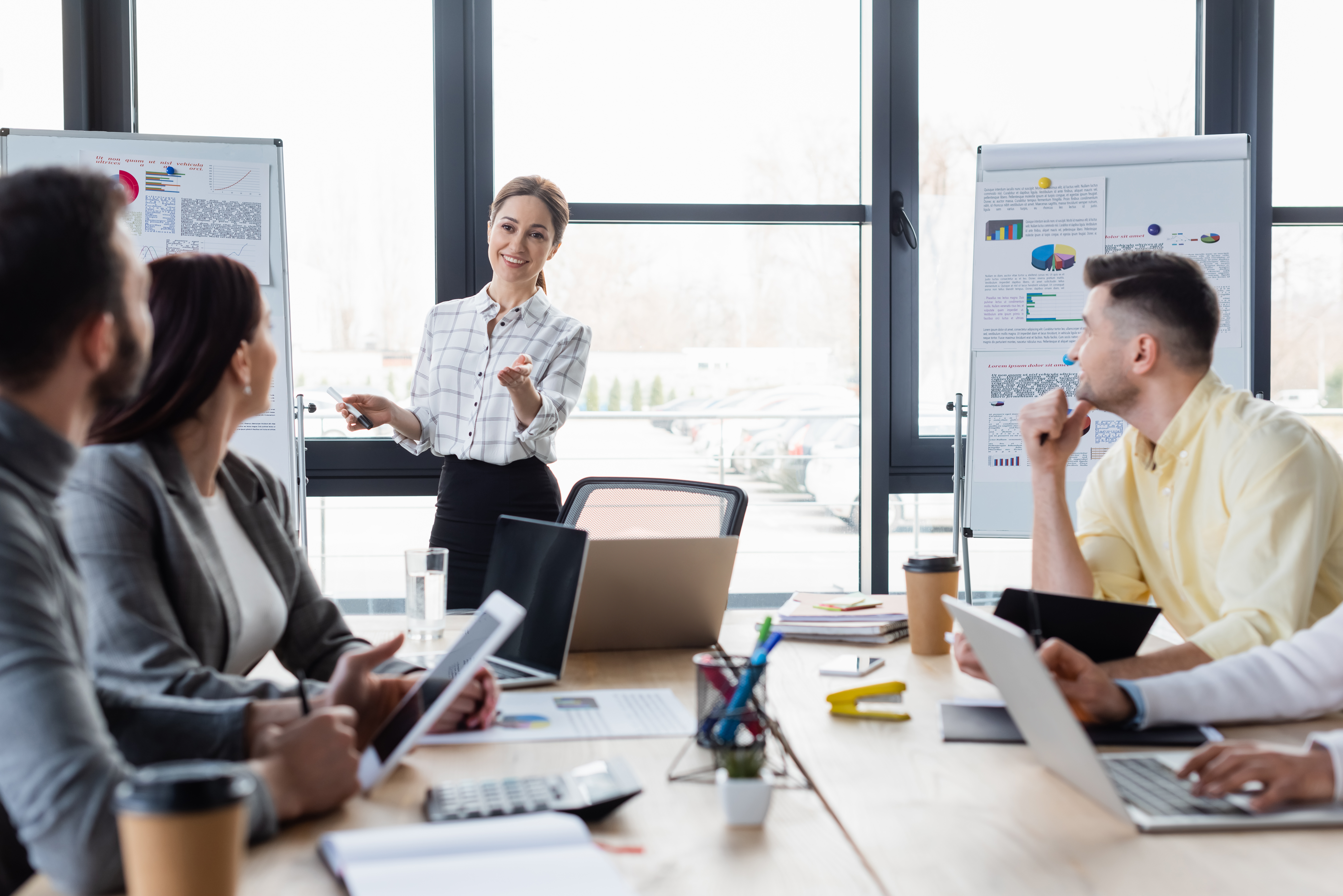 Smiling businesswoman pointing near blurred colleagues and flipc Synchrones Auftragsmanagement