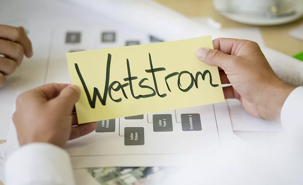 Karteikarte mit der Aufschrift "Wertstrom" in der Hand gehalten von einer Person mit Hemd